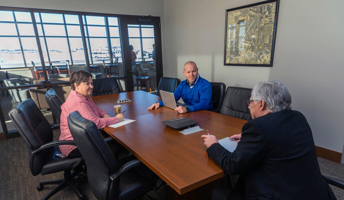 three individuals meeting in Maverick Air Center conference room